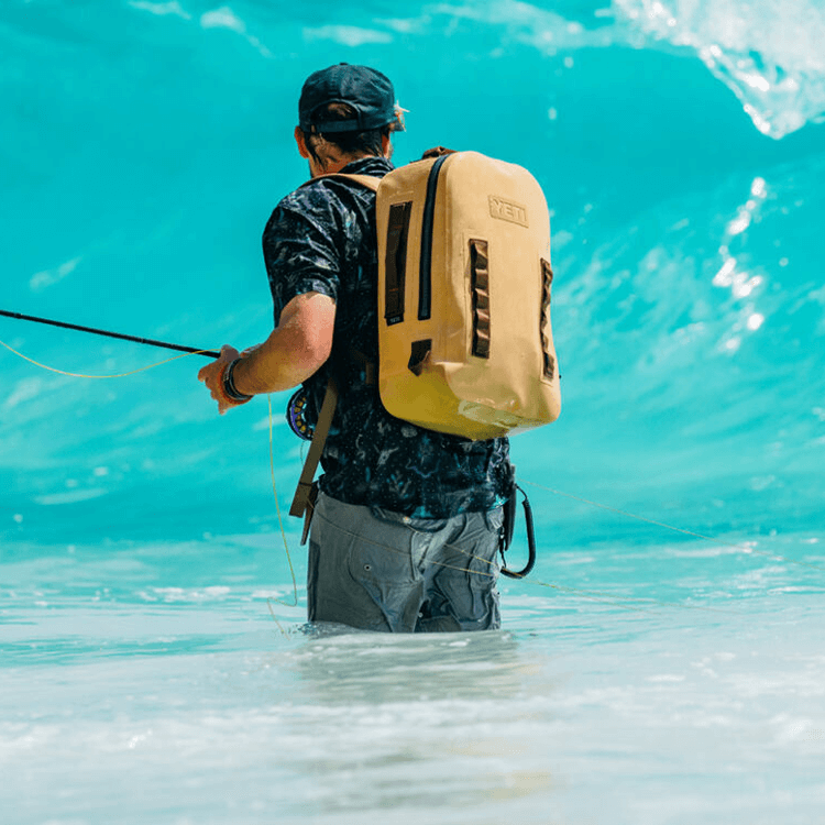 Man fishing with while wearing a yeti backpack