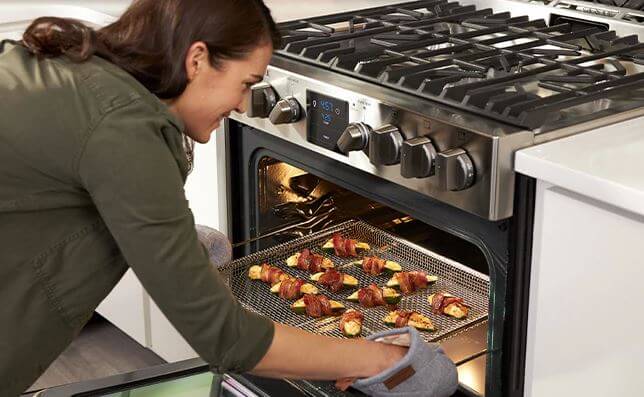Frigidaire Professional Ranges for slick slider section woman pulls food out of oven