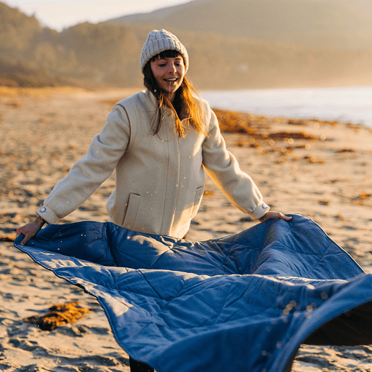 Woman putting Yeti blanket on a beach