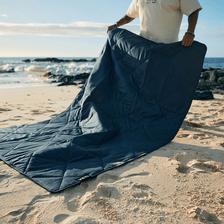 Man putting Yeti blanket on a beach