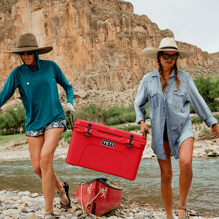 People carrying a Yeti hard cooler